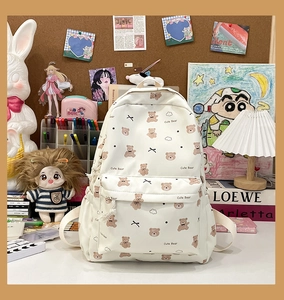 Close-up of cream backpack featuring cute brown bear patterns and multi-pocket design