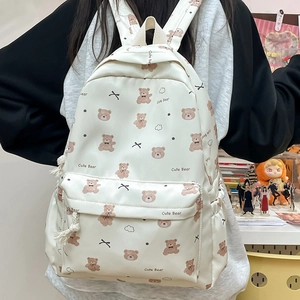Detail of white backpack featuring brown cartoon bear prints and cute black bow accents