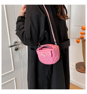 Pink quilted crossbody bag with metal flower clasp and chain strap on a model