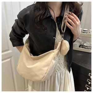 Detail of a beige corduroy hobo bag with a matching small round coin pouch on a model