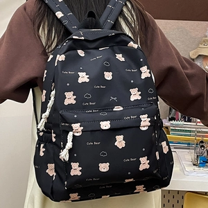 Detail of cute bear printed black canvas backpack with white rope zipper pulls and side pocket