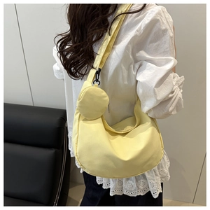 Detailed close-up of a light yellow nylon crescent bag featuring a detachable mini coin purse