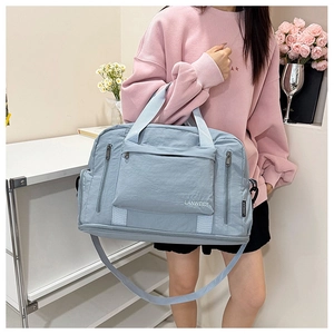 Detail of light blue waterproof nylon gym bag featuring front zipper and brand logo