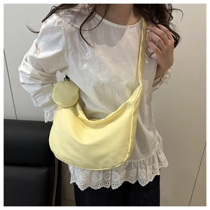 Detail view of a light yellow nylon crescent bag with a matching coin purse on model.