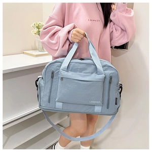 Detail of light blue waterproof travel bag with multiple zipper pockets and brand logo