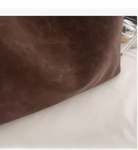Detailed macro view of vintage brown suede tote bag featuring a textured leather finish