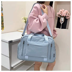 Blue waterproof nylon travel bag shown on shoulder with spacious compartments and strap