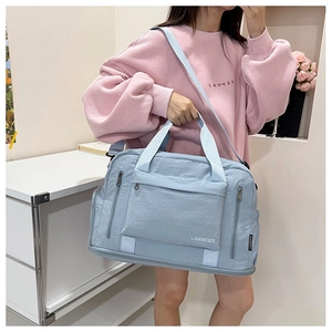 Detailed view of light blue travel bag with waterproof texture and sturdy shoulder straps