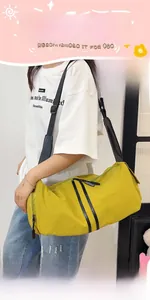 Detail of a ginger yellow cylindrical crossbody bag worn by a model in casual white t-shirt