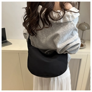 Rear view of a model wearing the black nylon half-moon shoulder bag in a casual setting
