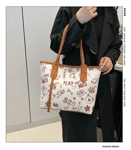 Vue détaillée du cabas à imprimé graffiti avec anses en cuir marron sur manteau noir