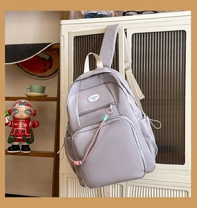 Dettaglio dello zaino viola per studenti appeso al mobile con ciondoli boho sulla zip
