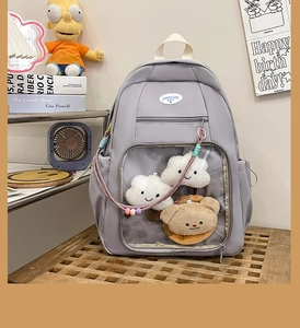 Dettaglio dello zaino viola con tasca in PVC trasparente, orsetto di peluche e nuvole