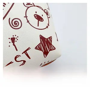 Gros plan du cuir grainé blanc avec des motifs d'ours et d'étoiles rouges imprimés