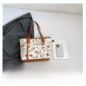Gros plan du grand sac cabas avec imprimé graffiti rouge et poignées contrastées brunes