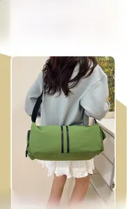 Detail view of a grass green cylinder yoga bag with black straps on a female model
