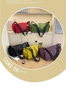 Detail view of five colorful waterproof nylon travel bags in red, green, black, yellow, and purple