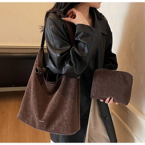 Detailed macro view of the dark brown faux suede tote bag and matching clutch accessory