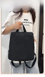 Detail of a black nylon backpack being held by a model with a side zipper feature
