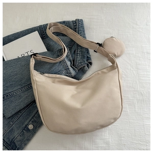 Detail view of beige nylon crossbody bag with adjustable strap and small round coin purse