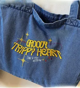 Détail de la broderie jaune et des motifs d'étoiles sur le sac fourre-tout en jean bleu