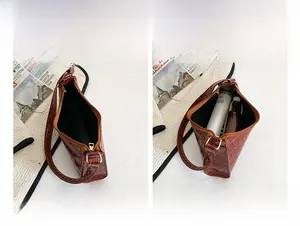 Detail view of brown crocodile texture mini handbag with zipper and internal storage space