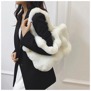 Détail d'un sac à bandoulière en fausse fourrure blanche porté avec un blazer noir chic