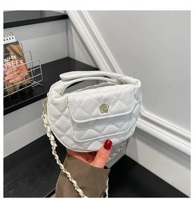 Detailweergave van een witte gewatteerde crossbodytas met gouden bloem en ketting