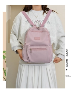 Detail view of the lightweight light pink nylon backpack with a zipper front pocket
