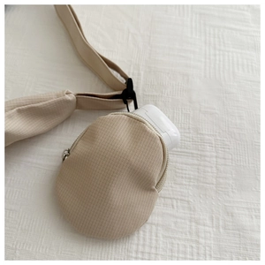 Detail of a beige nylon pouch for wireless earbuds attached to a wide crossbody strap
