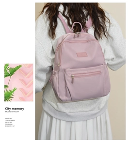 Detail view of the pink nylon backpack showing functional pockets and sleek urban design
