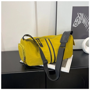Detail of bright yellow nylon travel bag with pleated texture and black straps on a shelf