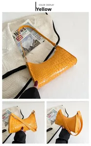 Detail of yellow crocodile embossed faux leather baguette bag with high gloss finish