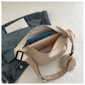 Detail view of beige nylon crossbody bag showing large capacity for books and mini pouch
