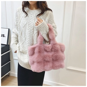 Gros plan du sac cabas en peluche rose avec texture en damier porté par un mannequin