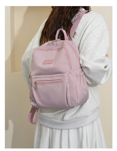 Detailed close-up of a pink nylon backpack featuring waterproof fabric and spacious pockets