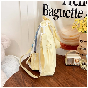Detail view of a yellow canvas tote bag side pocket with adjustable straps and zipper