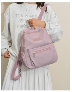 Detail of light pink nylon backpack with multi-pocket design and wide shoulder straps