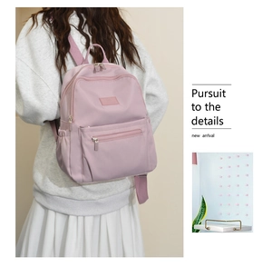 Detailed view of pink nylon backpack showing side water bottle pocket and metal zippers