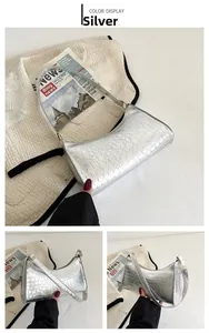 Detail view of silver crocodile embossed handbag with adjustable strap and metallic finish