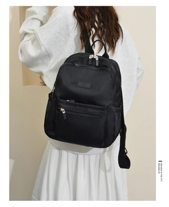 Detail view of stylish black nylon backpack with gold zippers and premium rubberized logo