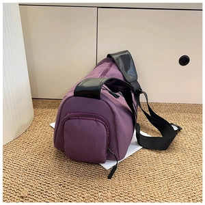 Detail view of purple nylon yoga bag with black handles and shoulder strap on rug