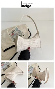 Detail view of beige crocodile texture shoulder bag with streamline design and smooth zipper