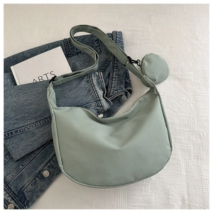 Close-up of sage green nylon hobo bag with mini round pouch on textured background
