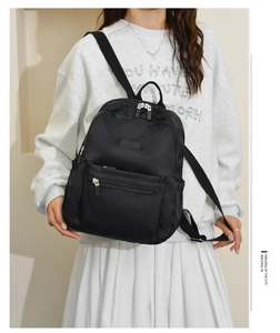 City lifestyle shot of a black nylon backpack worn by a model in a studio setting
