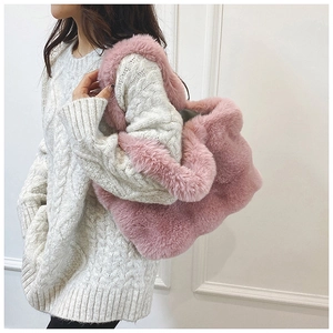 Gros plan sur un sac cabas en peluche rose avec texture douce et pull en maille blanc