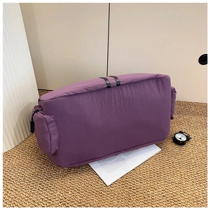 Detail view of large purple nylon travel bag showing side zipper compartment and webbing handle