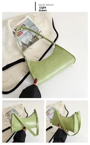 Detail view of light green crocodile pattern faux leather baguette bag with crescent shape