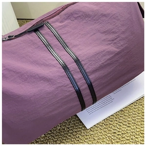 Detail of purple ruched travel bag fabric with black nylon webbing and zipper closure
