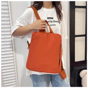 Detail view of the side zipper pocket on an orange nylon backpack with wide straps